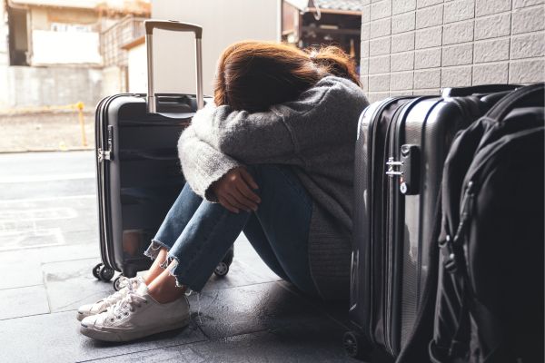 femme triste dans une gare SNCF avec sa valise