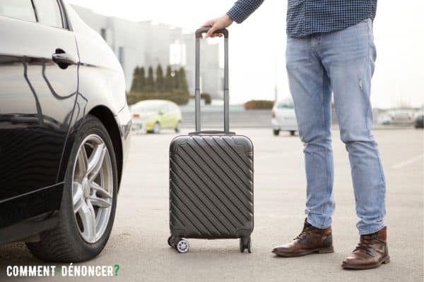 Homme avec sa valise en vacances devant une voiture en location